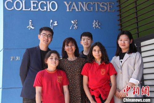 圖為11月6日，長(zhǎng)江學(xué)校校長(zhǎng)羅哈斯(Marcela Rojas Cantillana，左三)、國(guó)家漢辦駐智利漢語(yǔ)教師志愿者管理教師劉昌(左一)、長(zhǎng)江學(xué)校中文老師李媛媛(右)與學(xué)生們?cè)趯W(xué)校門前合影。<a target='_blank' >中新社</a>記者 余瑞冬 攝