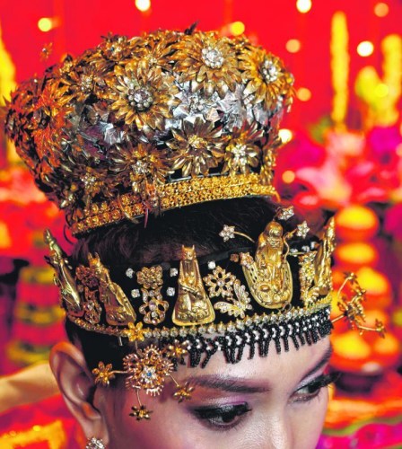 土生華人新娘頭戴裝飾珠寶的鳳冠，特別之處是額前飾以八仙形象的金頭套與花形鑲鉆金飾。 (新加坡《聯(lián)合早報》/梁麒麟 攝)