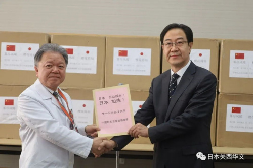 村上信五院長(左)代表院方從劉曉軍總領(lǐng)事(右)手中接受捐贈物資(日本《關(guān)西華文時報》微信公眾號/春平 攝)