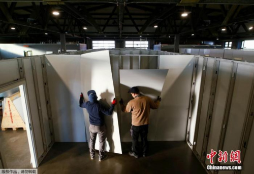 當?shù)貢r間3月25日，德國希勒斯海姆，工作人員和志愿者將市政大廳改建為醫(yī)療中心用于收治新型冠狀病毒患者。圖為工作人員和志愿者在安裝醫(yī)療中心隔間的墻面。