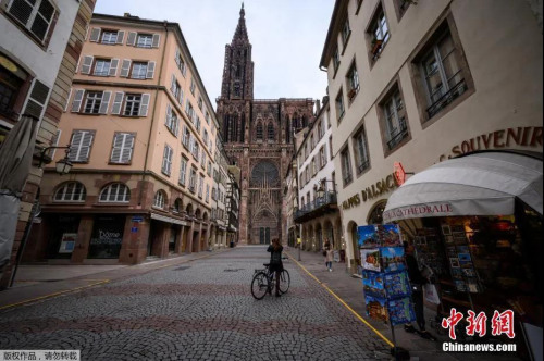 資料圖：法國“封城”生效前，斯特拉斯堡大教堂附近，一名婦女在街上騎自行車。