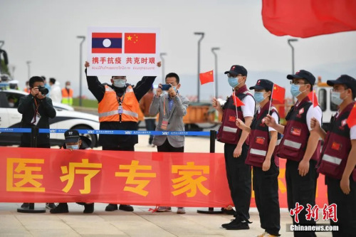 抗疫醫(yī)療專家組一行12人順利完成工作任務(wù)，乘包機(jī)平安飛抵云南昆明。圖為機(jī)場工作人員手舉印有中老兩國國旗的牌子迎接專家組。( <a target='_blank' >中新社</a>記者 劉冉陽 攝)