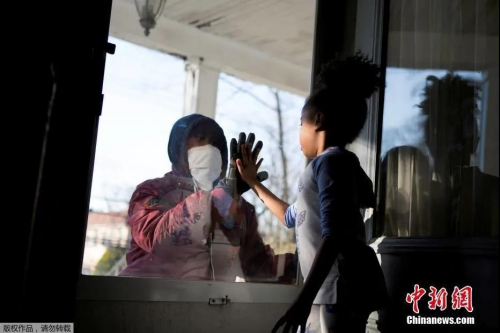 當(dāng)?shù)貢r(shí)間4月11日，美國紐約州新冠疫情持續(xù)嚴(yán)峻，新羅謝爾市的醫(yī)療行業(yè)從業(yè)人員哈希姆在工作期間與家人保持“社交距離”，和女兒隔門相會擊掌。