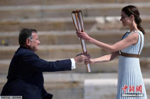 　當(dāng)?shù)貢r(shí)間3月19日，2020年東京奧運(yùn)會(huì)圣火交接儀式在雅典帕納辛奈科體育場(chǎng)進(jìn)行。圖為希臘奧委會(huì)主席斯皮羅斯·卡普拉洛斯接過火炬。