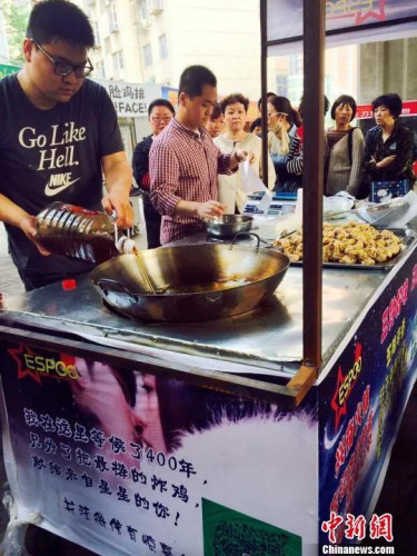 郭方正(左)正在往鍋里倒炸雞用的油，攤位邊等待的顧客已排起長隊(duì)?！〔苠P 攝