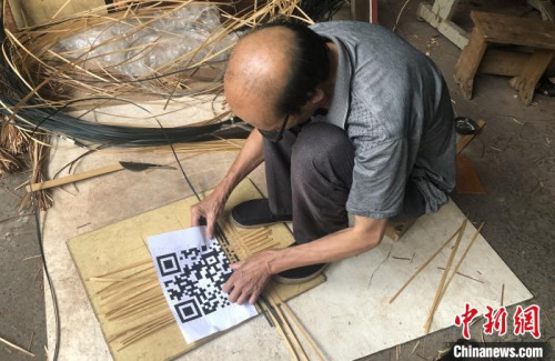 謝世仰將竹篾有序地?cái)[在地上，對(duì)照著打印出來(lái)的二維碼開(kāi)始編織?！∨砝蚍?攝