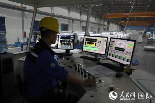 鼎力新材料公司的工廠投資1.2億美元，每年可以生產(chǎn)規(guī)格從5mic—2mm的鋁箔共計8萬噸。圖為技術(shù)員在操作切割鋁箔的軋機。人民網(wǎng)記者孫廣勇攝
