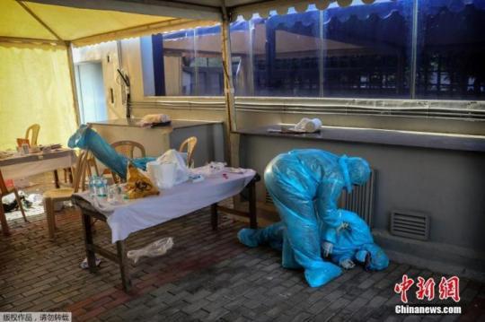 資料圖：印度新德里的核酸監(jiān)測點，一名衛(wèi)生工作者因疲勞過度倒下。Manish Swarup