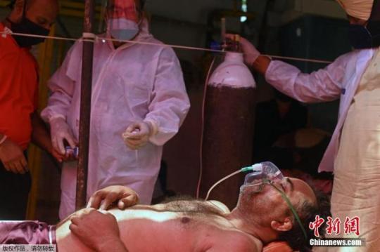 資料圖：當(dāng)?shù)貢r間4月26日，印度加茲阿巴德，一名新冠患者在路邊搭建的帳篷內(nèi)吸氧。