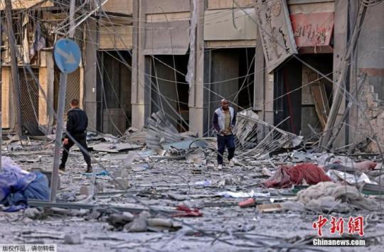 當(dāng)?shù)貢r間5月12日，巴以沖突期間，人們在受損嚴(yán)重的街頭行走。