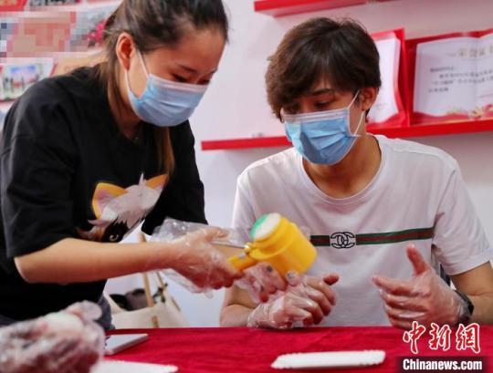 圖為社區(qū)居民和外國(guó)留學(xué)生一起制作月餅?！〔芙ㄐ?攝