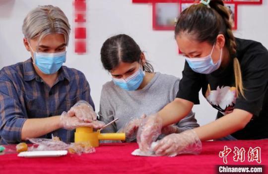 圖為社區(qū)居民和外國(guó)留學(xué)生一起制作月餅?！〔芙ㄐ?攝