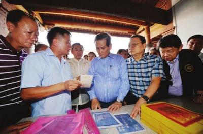 中國僑網(wǎng)黃年榮(中)在祖厝了解族譜。