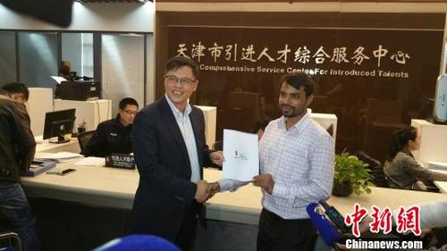 中國僑網(wǎng)資料圖:天津市外國專家局局長袁鷹(左)為南開大學克魯?shù)掀詹┦款C發(fā)天津首張《外國人工作許可證》。 劉家宇 攝