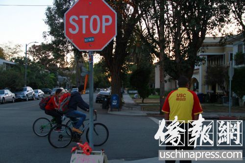 2名中國留學生騎車在“小黃衣”旁邊經過。(美國《僑報》/周慧一