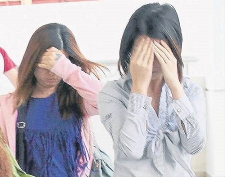 女被告李淑燕(前),雙手遮臉避開鏡頭。(馬來西亞《南洋商報(bào)》)