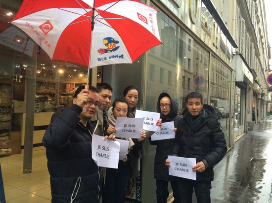 中國僑網(wǎng)法國華人服裝業(yè)總商會會長黃小中(右一)與十一區(qū)華商冒雨對遇難者表示聲援。(法國《歐洲時報》/孔帆 攝)