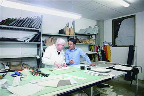 中國僑網(wǎng)意大利華僑夫婦胡小華和林愛菊的J.C皮包公司2014年收購了世界一流皮包奢侈品牌Desmo。圖為胡小華在設(shè)計室跟來自于古馳(GUCCI)的制版師交流皮包的款式設(shè)計。(圖片來源: 《溫州晚報》)