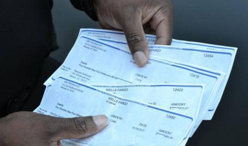 警方探員出示一疊假支票給記者看。(美國《僑報》)