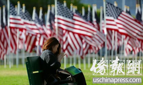 一名女子在旗海旁的長(zhǎng)椅上休息。(美國(guó)《僑報(bào)》/邱晨