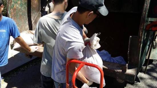 幾名華裔男子快速的將白色袋子搬上卡車離去。(美國《世界日報》/黃伊奕