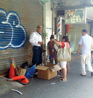該小販(左)經常出沒在法拉盛售賣仿冒包。(美國《星島日報》)