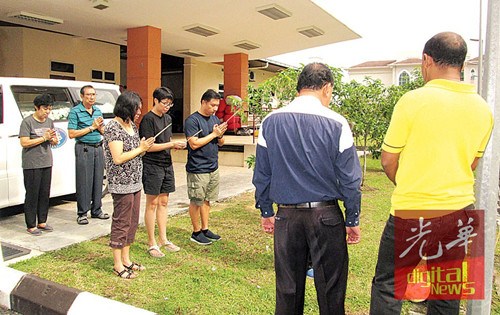 死于心臟病爆發(fā)年邁夫婦的3名子女及親友于醫(yī)院太平間,持香隨道士念經作法。(馬來西亞《光華日報》)