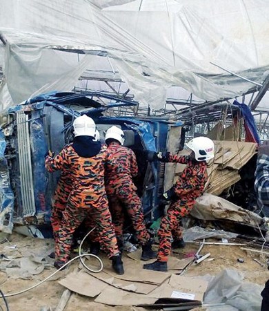 羅里在意外后嚴(yán)重毀損,消拯人員趕往現(xiàn)場(chǎng)展開救援工作。(馬來(lái)西亞《光華日?qǐng)?bào)》)