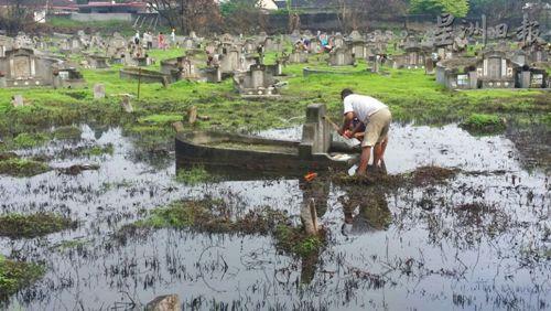 中國(guó)僑網(wǎng)市民被迫在猶如水中小島的義山山頭祭拜先人,非常狼狽及不便。(圖:星洲日?qǐng)?bào))