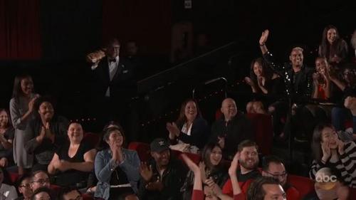 中國僑網奧斯卡明星去影院發(fā)零食,坐在圖片中右側穿黑白條毛衣的羅睿雪驚喜捂住嘴。(美國《世界日報》/羅睿雪提供)