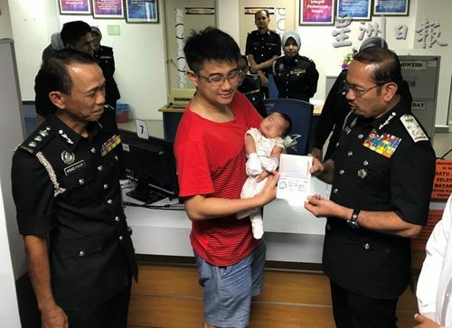 中國僑網(wǎng)慕斯達法(右)移交護照給民眾。(馬來西亞《星洲日報》)