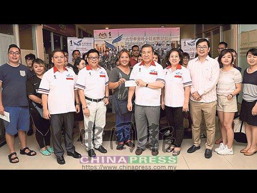 中國僑網(wǎng)林順平(右5)移交支票給借貸者。(馬來西亞《中國報(bào)》)