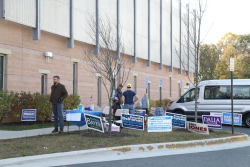 中國(guó)僑網(wǎng)選舉站外插滿(mǎn)了參選人的牌子,還有義工分發(fā)參選人資料。(美國(guó)《世界日?qǐng)?bào)》/羅曉媛 攝)
