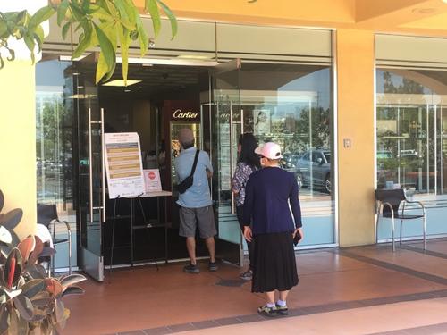 中國(guó)僑網(wǎng)店家為客人測(cè)量體溫。(美國(guó)《世界日?qǐng)?bào)》/王全秀子 攝)