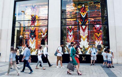 人們正在走過法國巴黎某名品店門前。(彭博社)