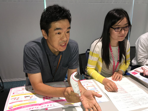 某品牌公司的人員在講述新款離子美容儀的開發(fā)秘話和使用方法。(日本新華僑報網(wǎng))