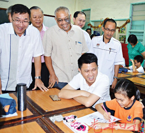 張盛聞(坐者左)為正在練習(xí)作業(yè)的小六考生加油打氣