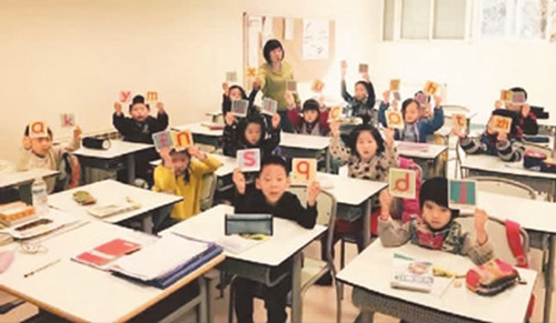 圖為應(yīng)紅老師和剛?cè)雽W(xué)的一年級新生。