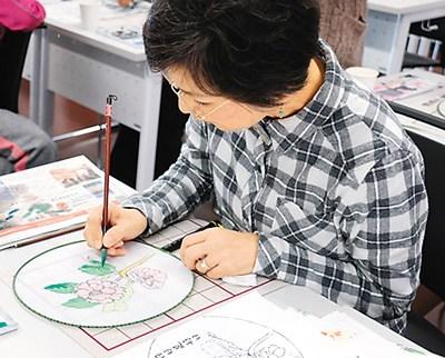 中國(guó)僑網(wǎng)認(rèn)真學(xué)畫團(tuán)扇