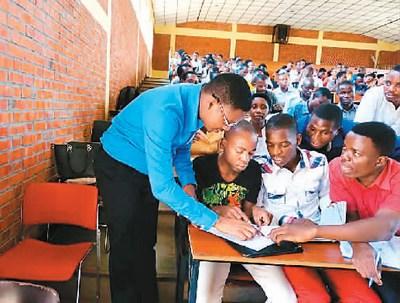 中國(guó)僑網(wǎng)布隆迪大學(xué)孔子學(xué)院漢語(yǔ)教師弗迪南(左)在為學(xué)生上課。