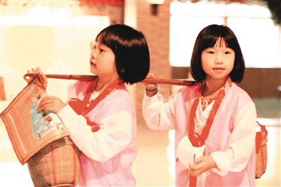 中國(guó)僑網(wǎng)圖為小朋友在輔導(dǎo)員的指引下完成用扁擔(dān)挑貨物的任務(wù)。(圖片來源于網(wǎng)絡(luò))