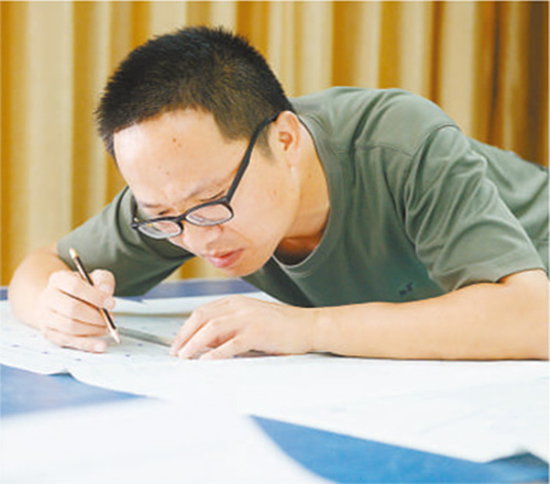 周湘虎正在核對(duì)修改施工圖紙。