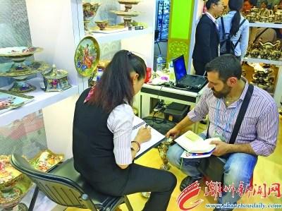 中國僑網(wǎng)圖為潮州市參展企業(yè)營銷人員與國外采購商開展訂單洽談。 本報記者 曾曉純 楊燕芳 攝