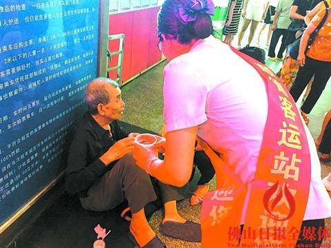 中國僑網(wǎng)工作人員在旁邊照料老人。(區(qū)嘉燕 攝)