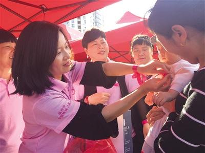 中國(guó)僑網(wǎng)志愿者為小女孩系上粉紅絲帶。 莊越 攝