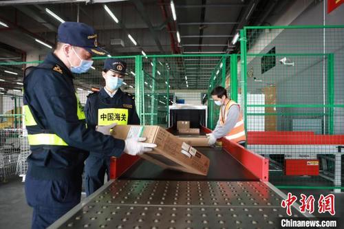 中國僑網(wǎng)拱北海關(guān)所屬港珠澳大橋海關(guān)關(guān)員在港珠澳跨境電商作業(yè)中心驗放包裹 樊詩如 攝