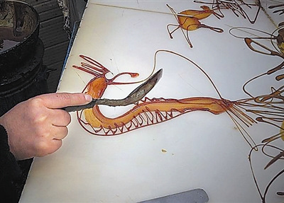 中國僑網(wǎng)龔保欣正在創(chuàng)作幽蘭糖畫。