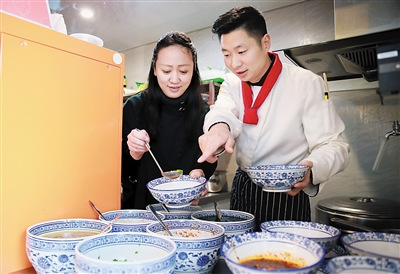 來自新加坡的史曉露(左)在程勇的指導(dǎo)下學(xué)習(xí)打調(diào)料。(苑鐵力