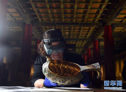 工作人員查看一款準備展出的畫琺瑯水盛器