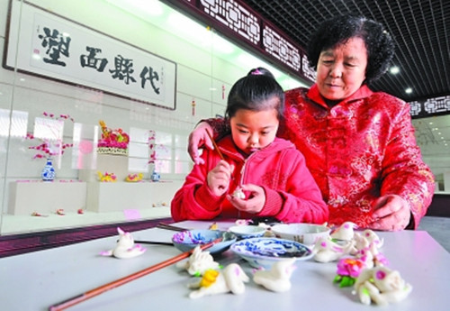 山西非物質(zhì)文化遺產(chǎn)代縣面塑傳人張桂英正在傳授孫女面塑手藝(資料圖)